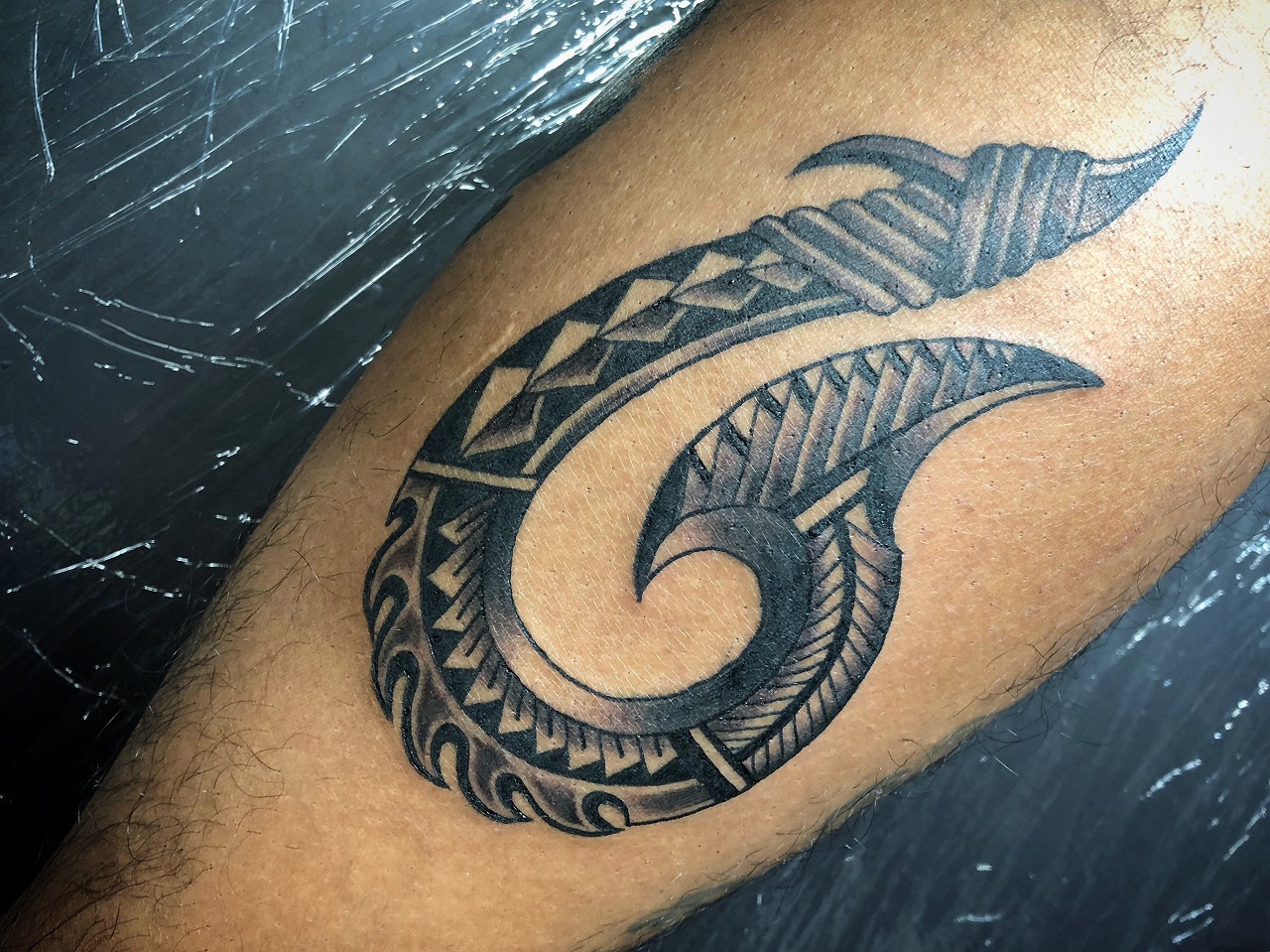 足のふくらはぎにフィッシュフックのトライバルタトゥーtribaltattoo
