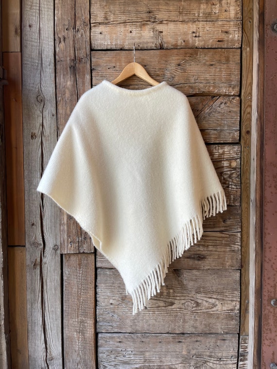 クリームホワイトのウールポンチョケープ、フリンジ付きの白い